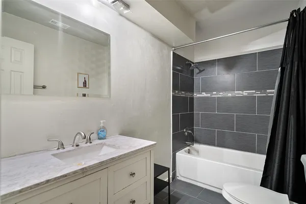 a bathroom with a granite countertop sink a toilet and bathtub