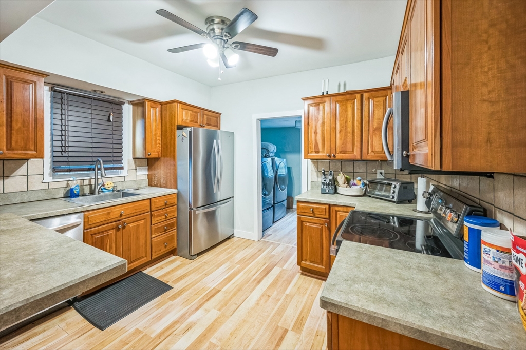 67 Meadow Street Framingham, MA 01701 - Photo 4 of 15 a kitchen with stainless steel appliances granite countertop a refrigerator a sink dishwasher a stove and white countertops with wooden floor
