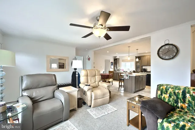 a living room with furniture a clock and a ceiling fan