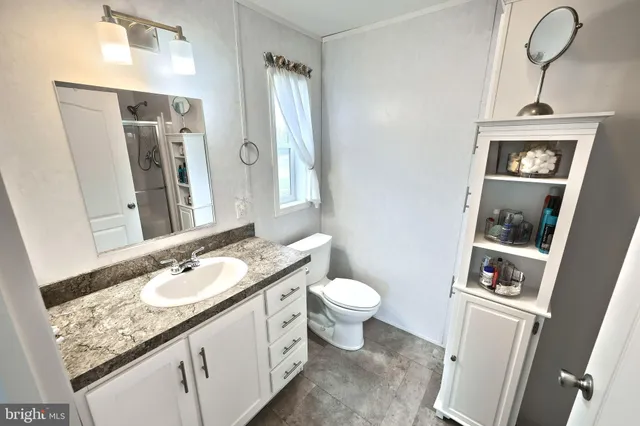 a bathroom with a granite countertop sink mirror vanity and toilet
