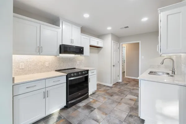 a kitchen with granite countertop a sink stove and cabinets