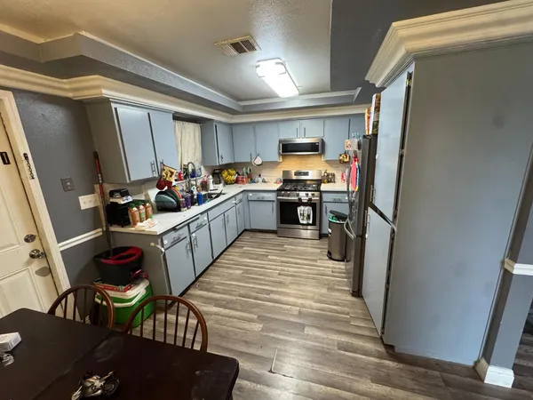 a kitchen with lots of appliances and wooden floor