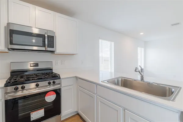a kitchen with white cabinets a sink and a stove with wooden floor