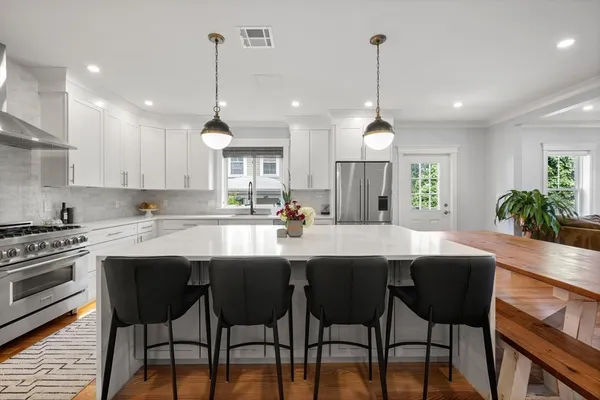 a kitchen with stainless steel appliances a dining table chairs stove and white cabinets