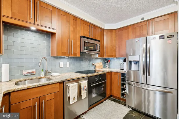 a kitchen with stainless steel appliances granite countertop a refrigerator stove a sink and dishwasher with wooden cabinets