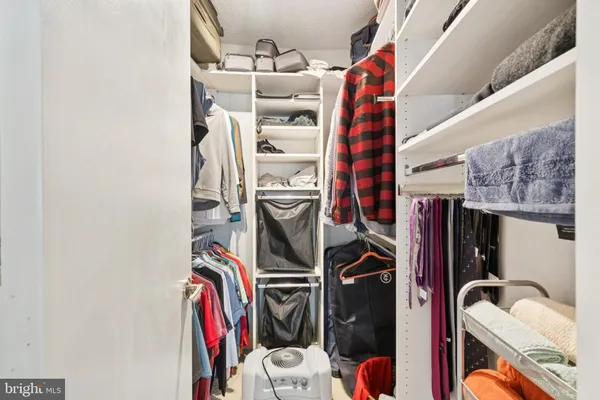 a view of walk in closet with clothes and shoes
