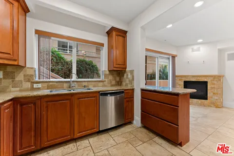 a kitchen with stainless steel appliances granite countertop wooden cabinets a sink and a large window