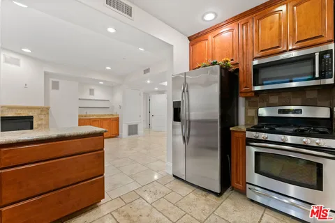 a kitchen with stainless steel appliances granite countertop a refrigerator stove and microwave