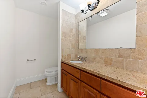 a bathroom with a granite countertop sink a toilet and a mirror
