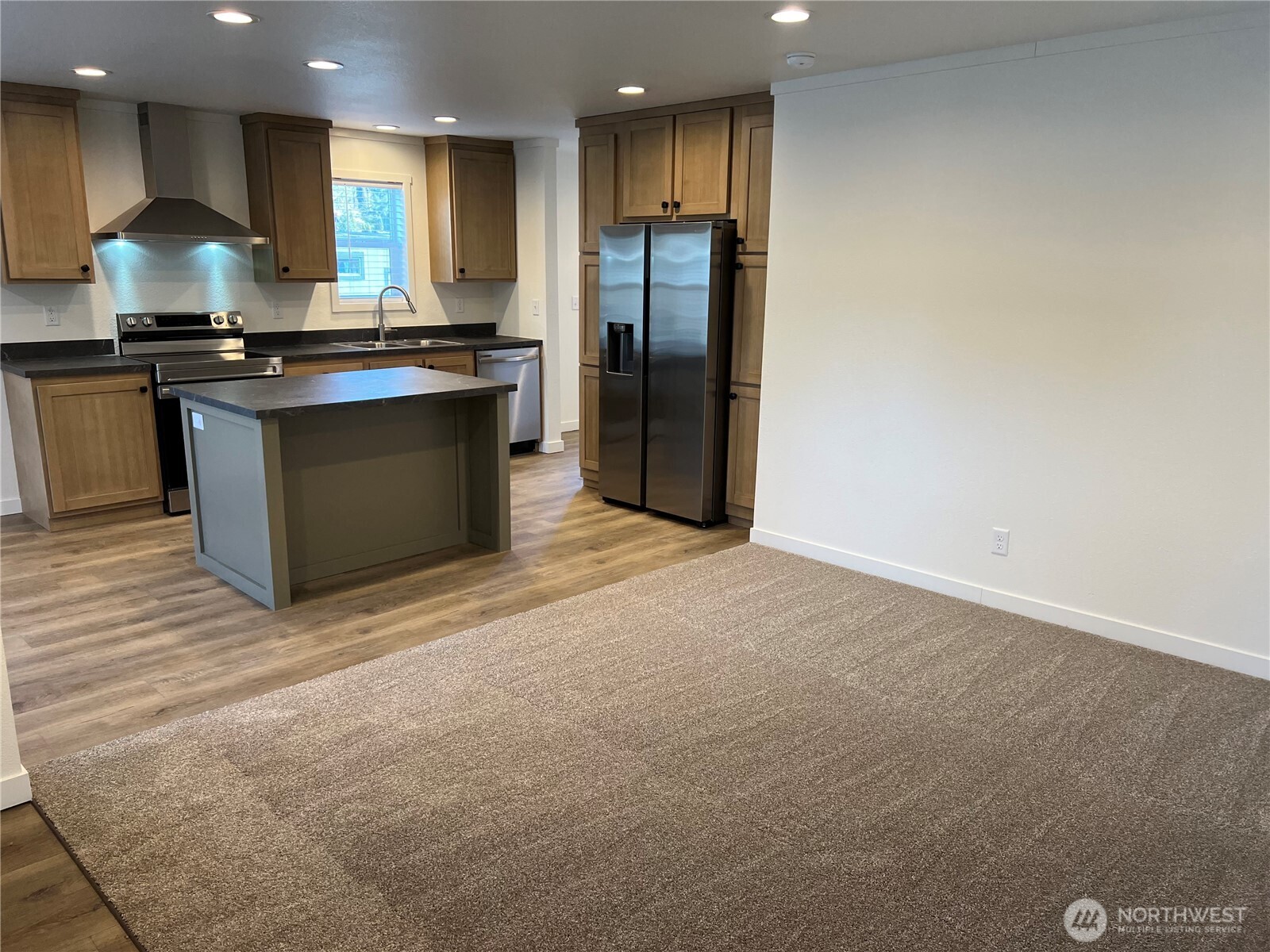 512 Southwest Berry Lake Road, Unit 21 Port Orchard, WA 98367 - Photo 3 of 19 a kitchen with stainless steel appliances granite countertop a stove a refrigerator a sink a oven with wooden cabinets and floor