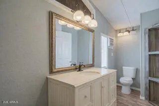 a bathroom with a granite countertop sink a toilet and a mirror