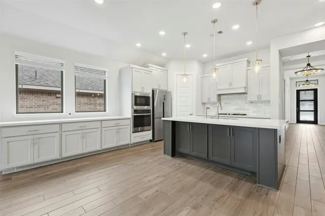 a large white kitchen with kitchen island a sink stainless steel appliances and cabinets