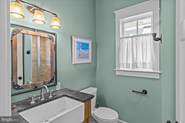 a bathroom with a granite countertop toilet a sink and a mirror