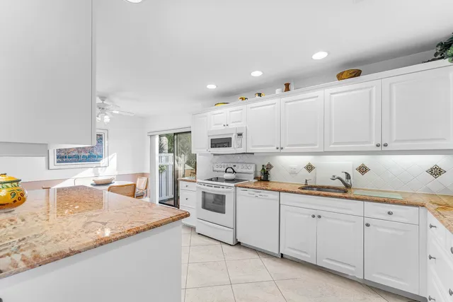 a kitchen with granite countertop white cabinets and white appliances