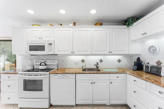 a kitchen with white cabinets and refrigerator
