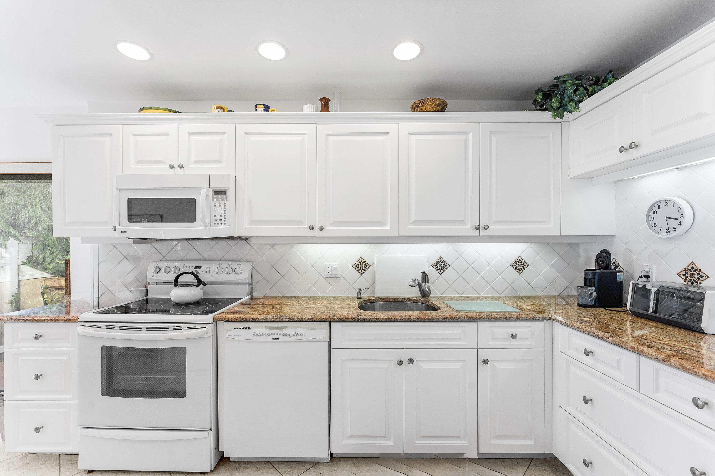 61 Eastgate Drive, Unit A Boynton Beach, FL 33436 - Photo 14 of 54 a kitchen with granite countertop white cabinets and white appliances