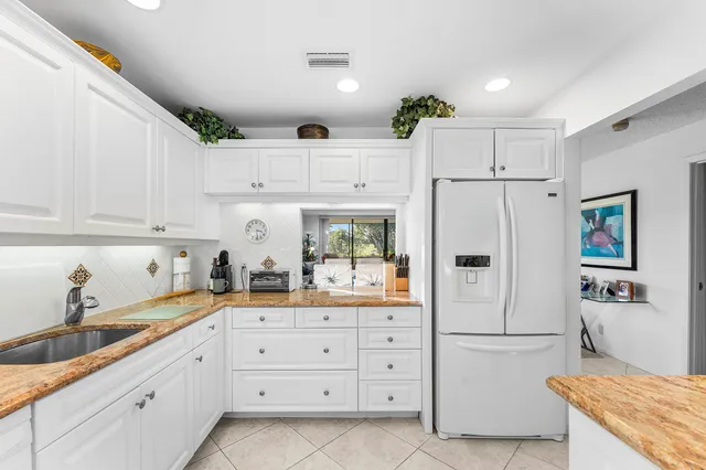 a kitchen with stainless steel appliances granite countertop white cabinets sink and white appliances