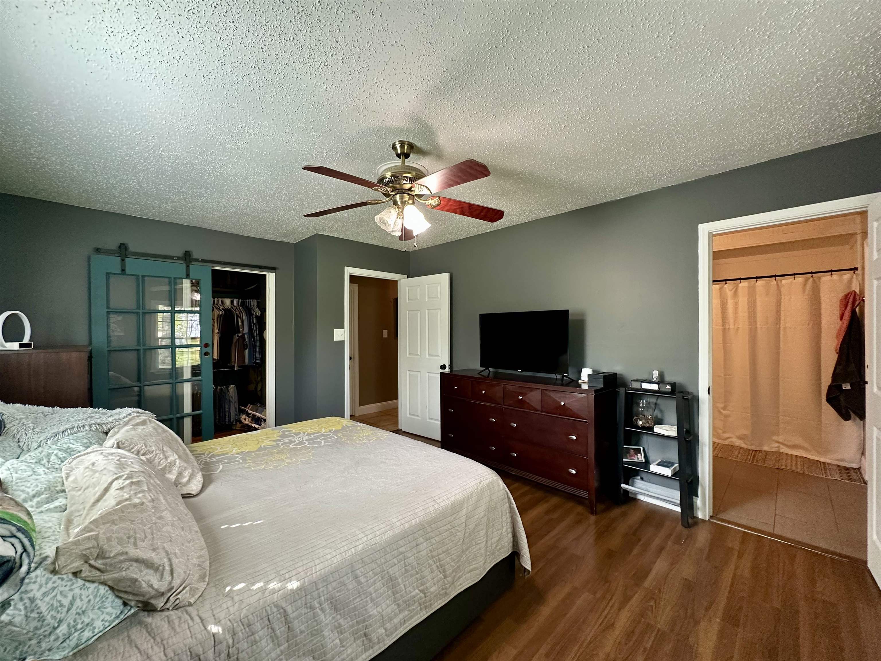 1230 Joann Road Somerville, TN 38068 - Photo 11 of 28 Bedroom featuring connected bathroom, a textured ceiling, dark wood-style floors, a ceiling fan, and a walk in closet
