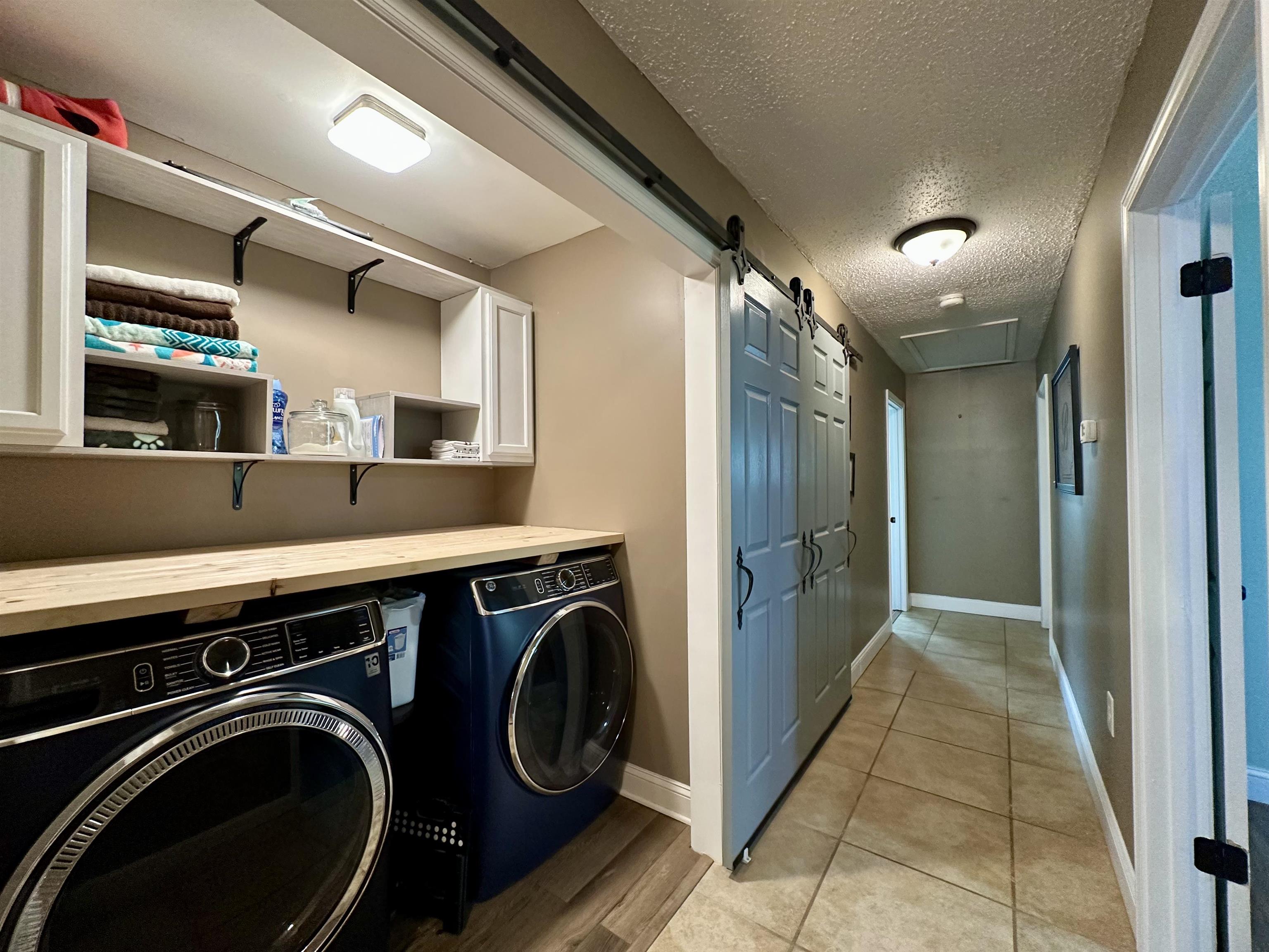 1230 Joann Road Somerville, TN 38068 - Photo 19 of 28 Laundry room with a barn door, a textured ceiling, washing machine and clothes dryer, and light tile patterned floors