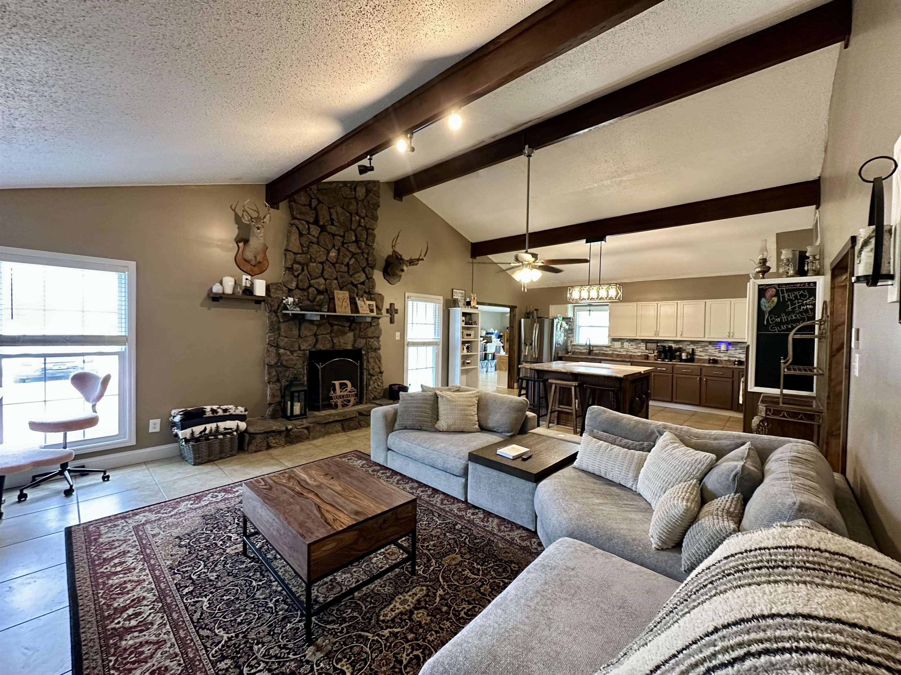 1230 Joann Road Somerville, TN 38068 - Photo 6 of 28 Living room with a stone fireplace, ceiling fan, light tile patterned floors, and beam ceiling