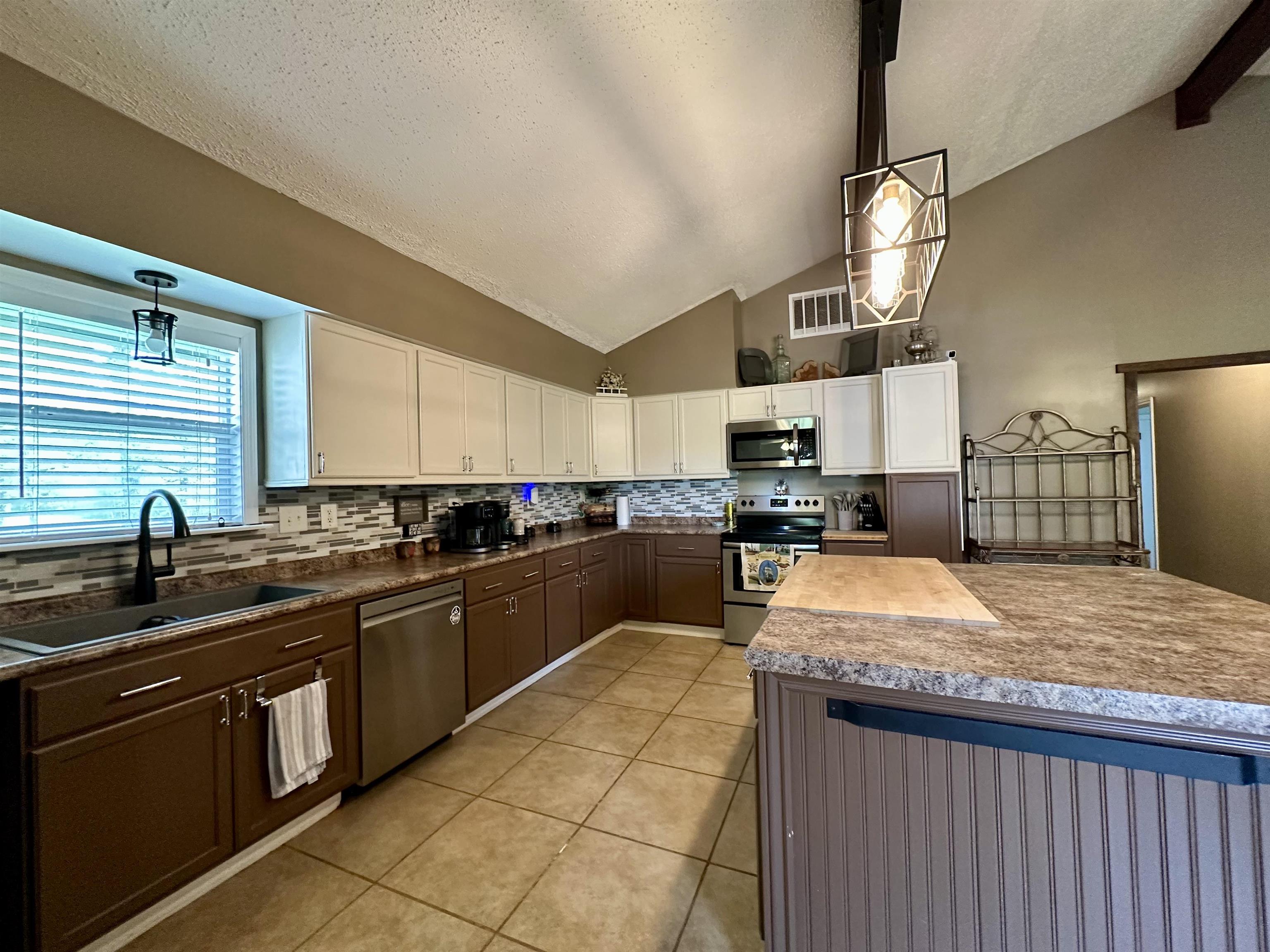 1230 Joann Road Somerville, TN 38068 - Photo 8 of 28 Kitchen with hanging light fixtures, decorative backsplash, stainless steel appliances, two tone color scheme, and light tile patterned floors