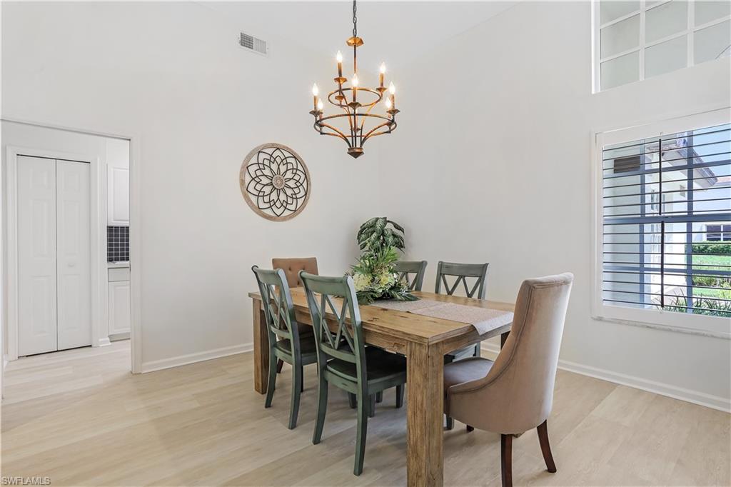 7699 Groves Road Naples, FL 34109 - Photo 13 of 30 a view of a dining room with furniture wooden floor and a chandelier