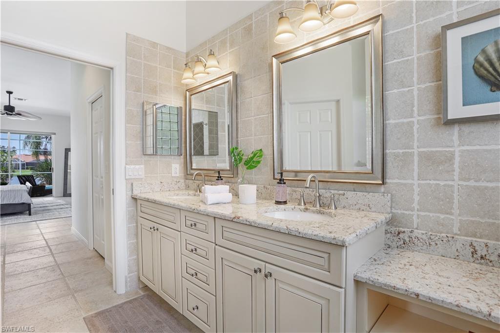7699 Groves Road Naples, FL 34109 - Photo 19 of 30 a bathroom with a granite countertop sink double vanity and a mirror