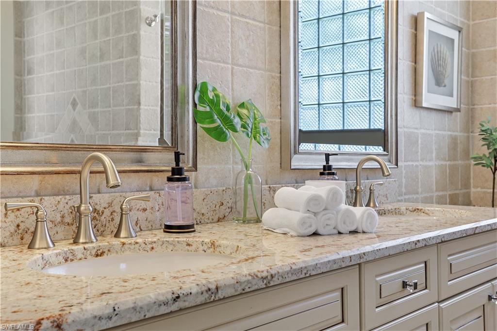 7699 Groves Road Naples, FL 34109 - Photo 21 of 30 a bathroom with a granite countertop sink and a potted plant
