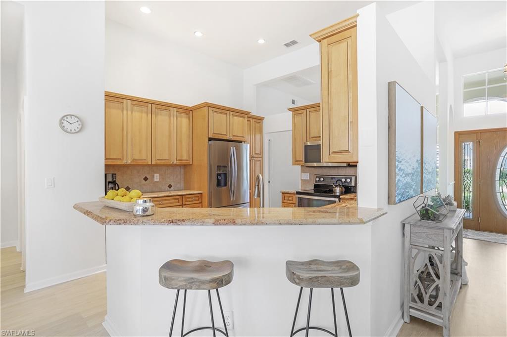 7699 Groves Road Naples, FL 34109 - Photo 10 of 30 a kitchen with stainless steel appliances granite countertop a kitchen island a stove and a refrigerator