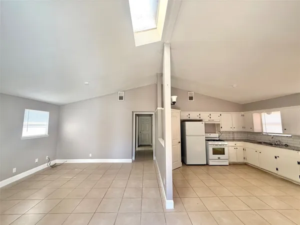a large kitchen with a refrigerator a stove top oven and white cabinets