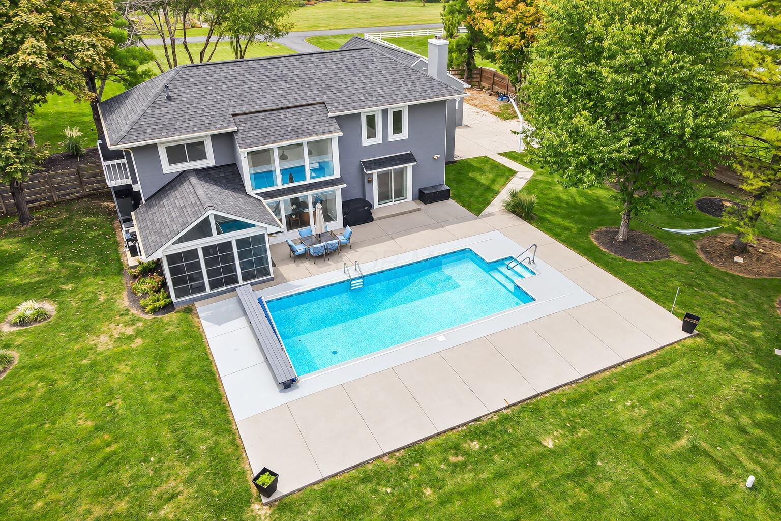 7140 Cook Road Powell, OH 43065 - Photo 28 of 87 Stucco exterior with a gabled roofline, screened porch, and an in-ground swimming pool with a surrounding concrete patio