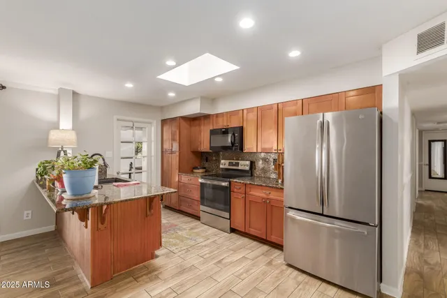a kitchen with stainless steel appliances granite countertop a refrigerator and a stove top oven