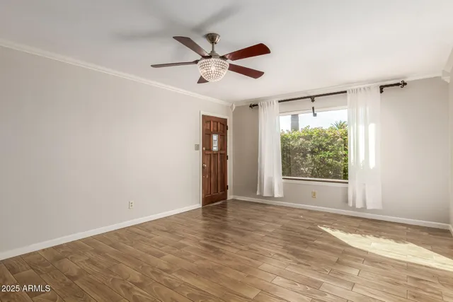 a view of an empty room with wooden floor and a window