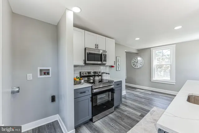 a kitchen with stainless steel appliances granite countertop a stove top oven a sink dishwasher a dining table and chairs with wooden floor