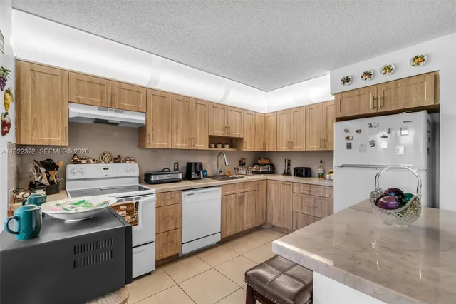 a kitchen with granite countertop a sink stainless steel appliances and white cabinets