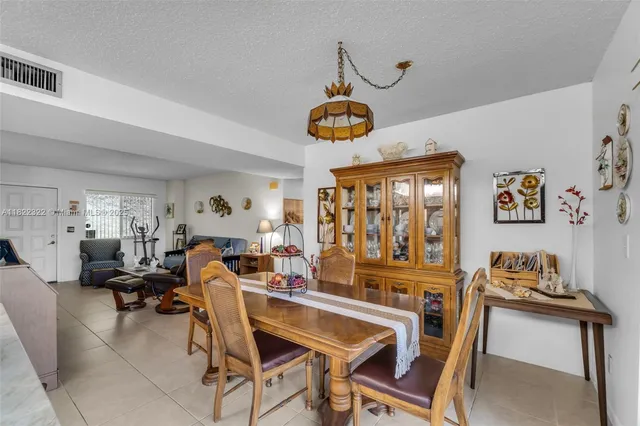 a view of a dining room and livingroom with furniture wooden floor a rug a painting and a chandelier