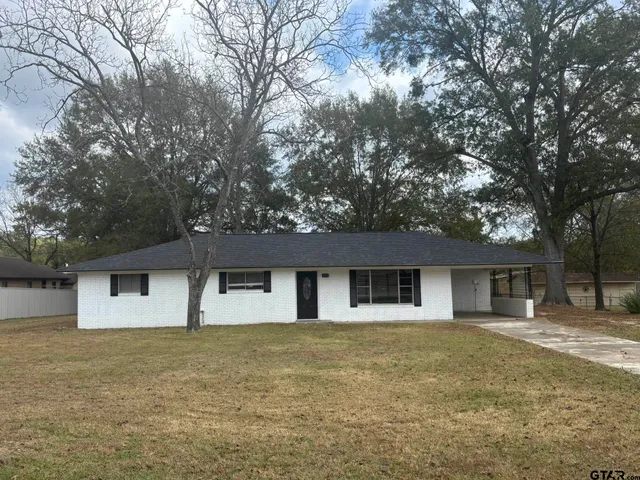 a front view of house with yard and trees in the background