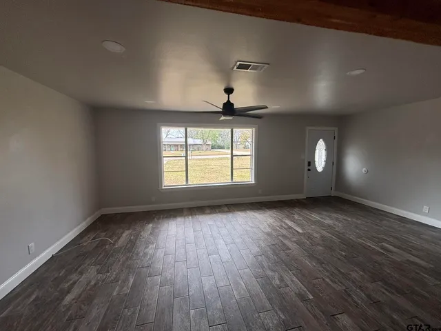 an empty room with wooden floor and windows