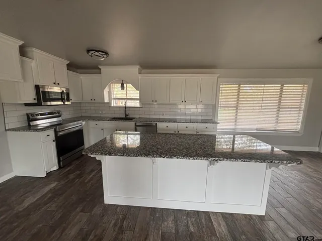 a kitchen with granite countertop cabinets stainless steel appliances and a sink