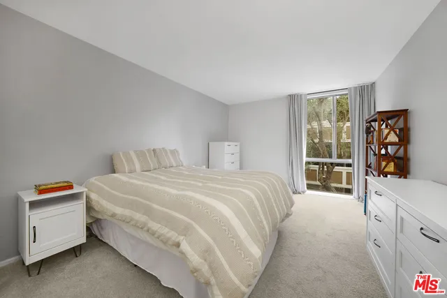 a bedroom with a bed and a large mirror on the dresser