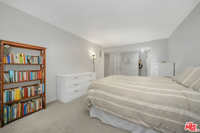 a spacious bedroom with a bed and a book shelf
