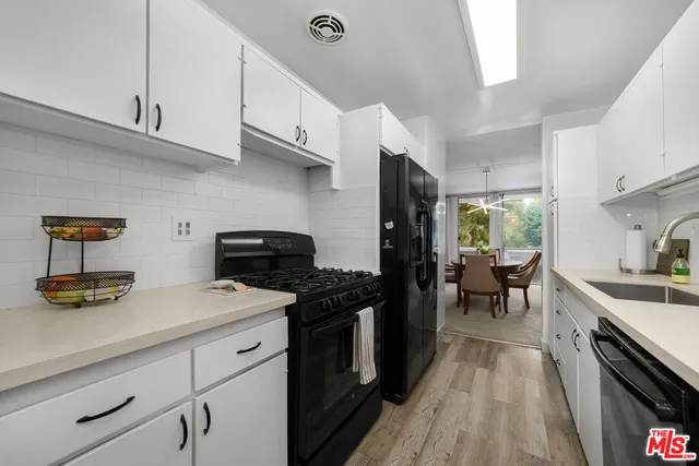 a kitchen with stainless steel appliances a stove a sink dishwasher and cabinets with wooden floor