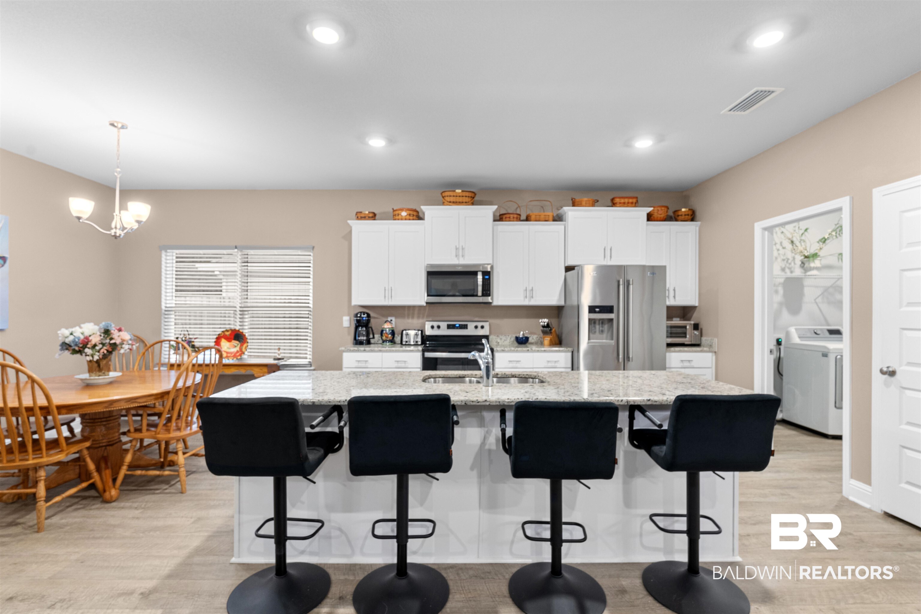 697 Calibre Street Fairhope, AL 36532 - Photo 6 of 18 Kitchen featuring a breakfast bar, light wood-style floors, stainless steel appliances, white cabinets, and light stone countertops
