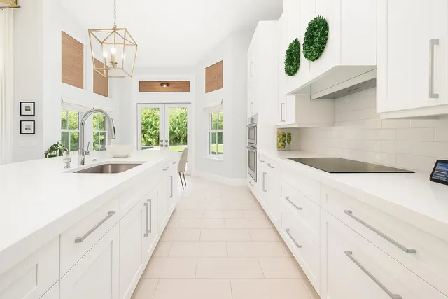 a large white kitchen with granite countertop a sink and a large window