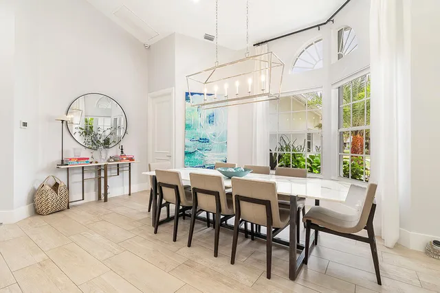 a dining room with wooden floor a chandelier a wooden table and chairs