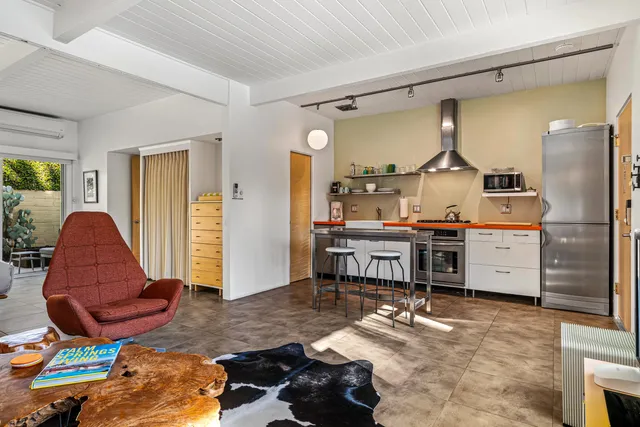 a living room with furniture a flat screen tv and kitchen view