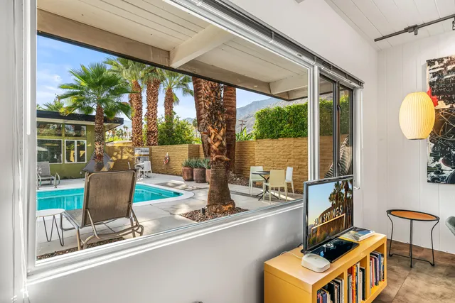 a view of a chairs and table in patio with a swimming pool