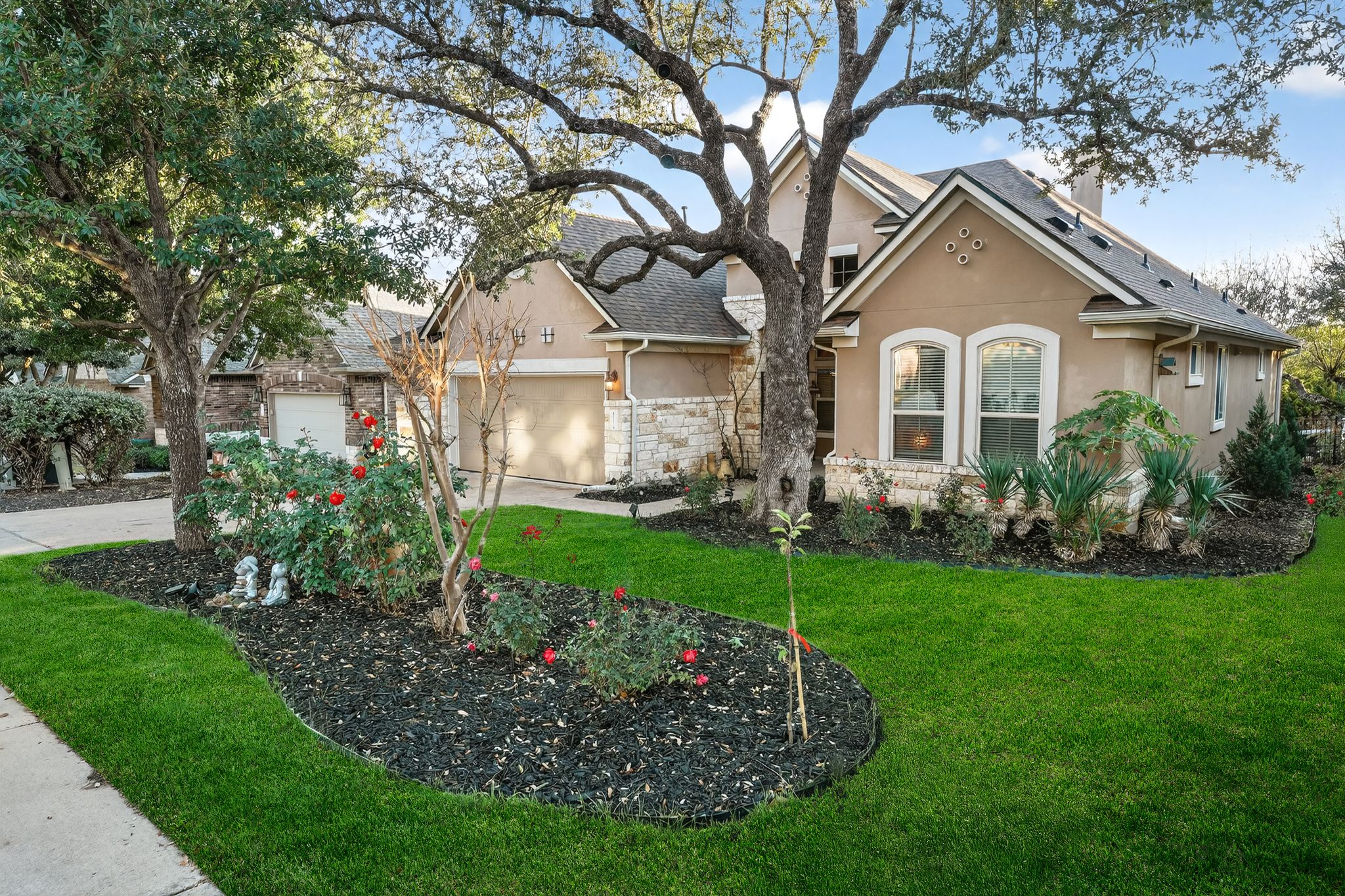 View of front facade featuring stucco siding, a front lawn, an attached garage, and driveway