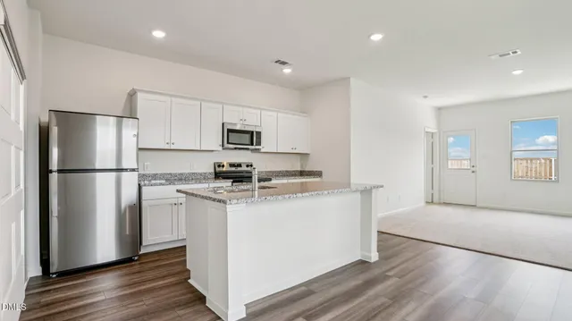 a kitchen with stainless steel appliances granite countertop a refrigerator a stove a sink and a microwave