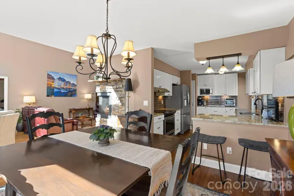 a view of a dining room and livingroom with furniture wooden floor a chandelier